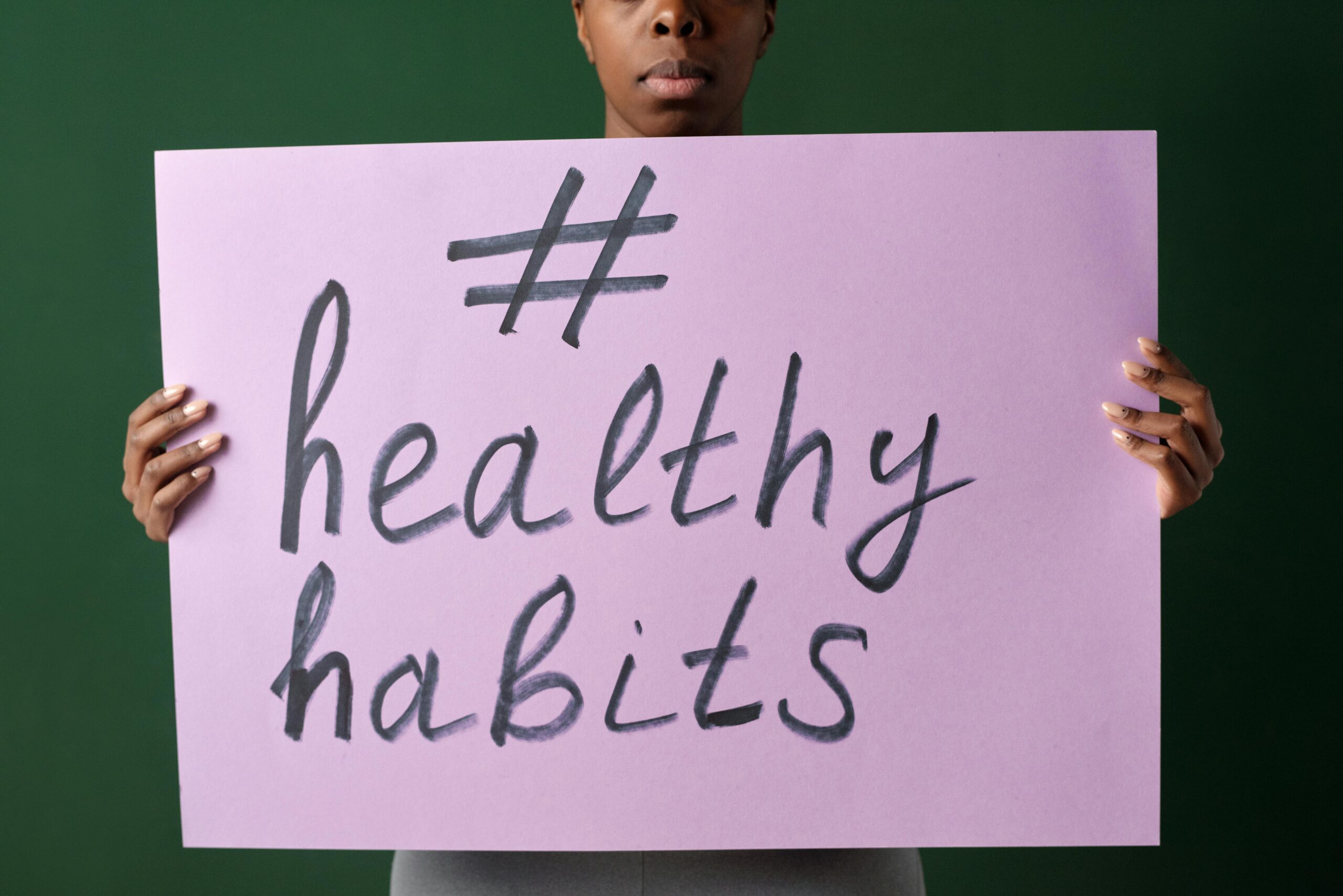 Person holding a "#healthyhabits" sign, emphasizing wellness.